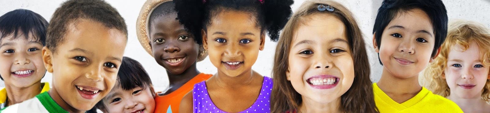 Several children of different ethnicities at daycare smiling and looking at the camera enjoying themselves