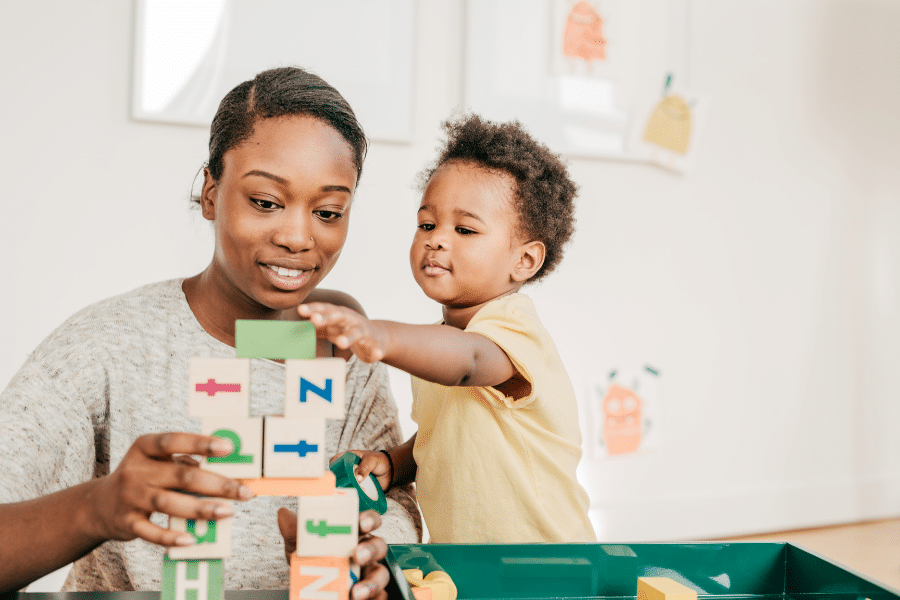 A women and a child smiling as they play with blocks together