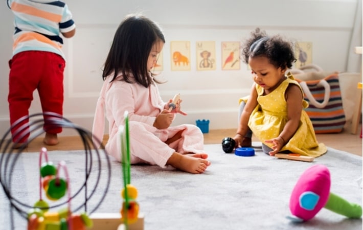 Young kids playing together on a carpet in a daycare facility