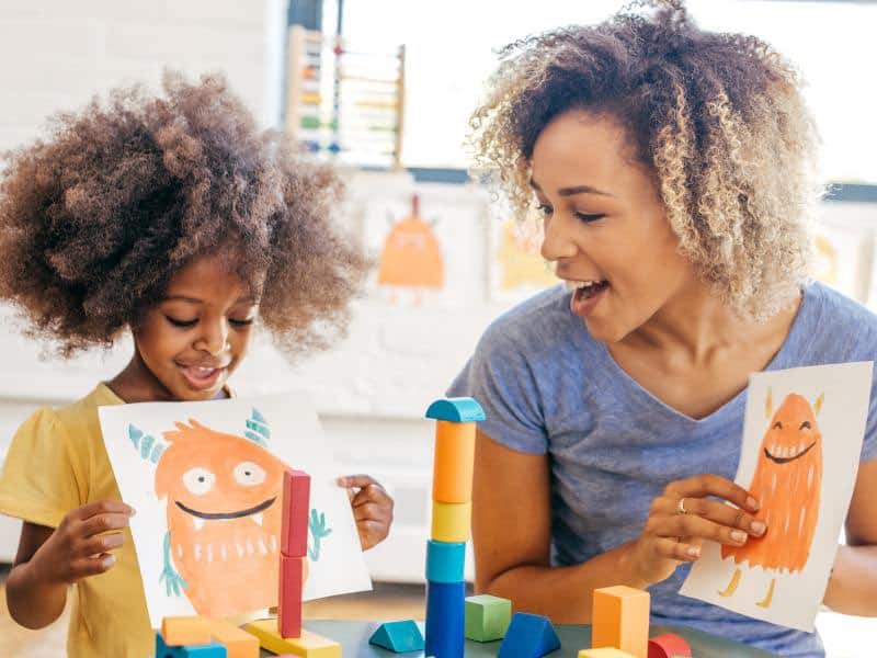 Lady and girl showing off artwork to each other